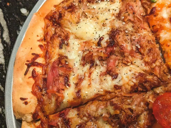 Slice of cheesy pizza with toppings.