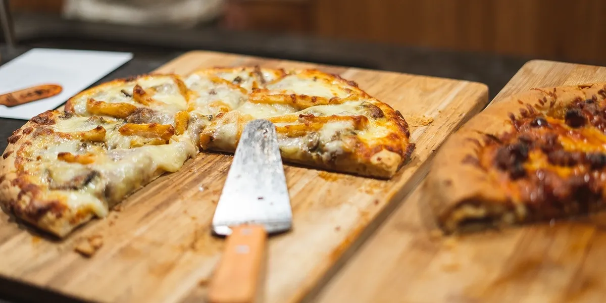 Pizza on wooden board with knife.