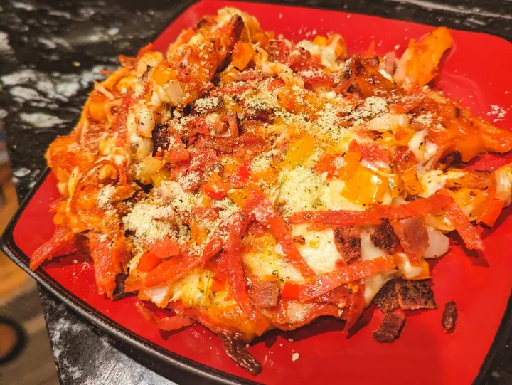 Cheesy nachos with toppings on red plate.