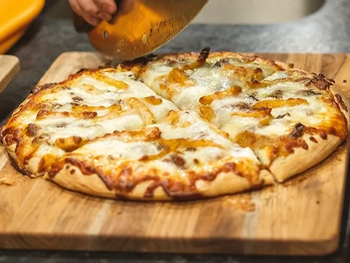 Cutting a freshly baked cheese pizza.
